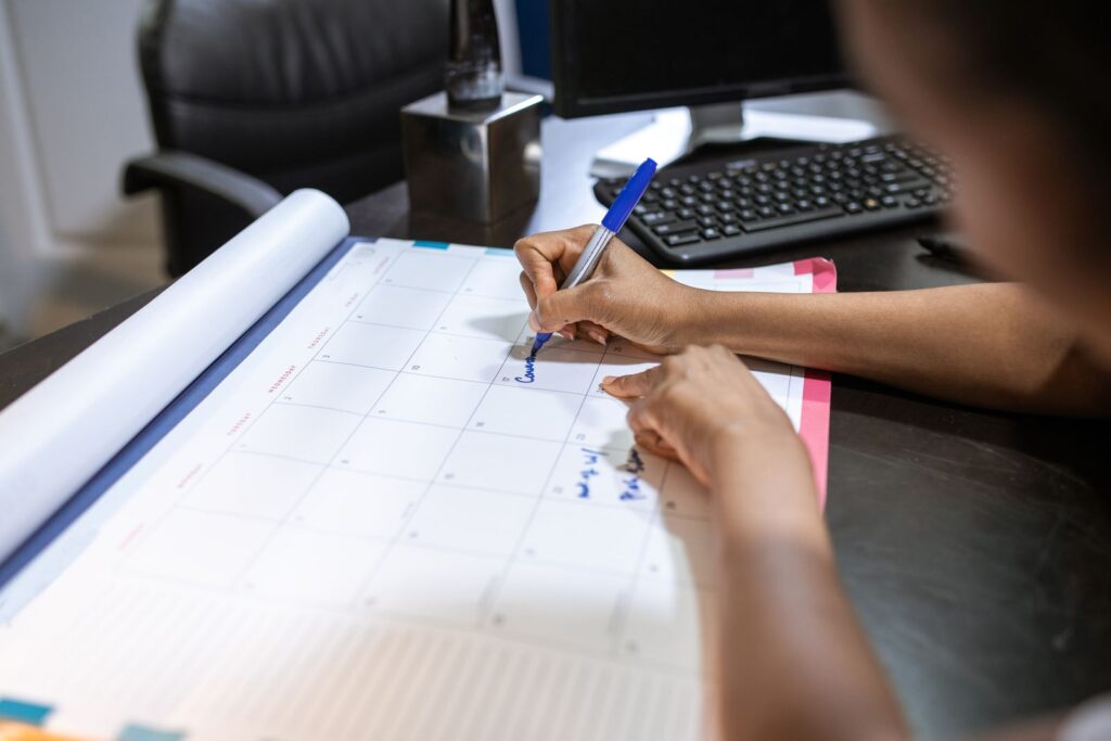 Persona che scrive le date di consegna sul calendario da scrivania